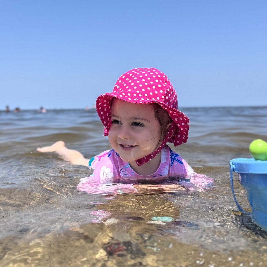 Liliya playing in the sea in her pink polka-dot hat